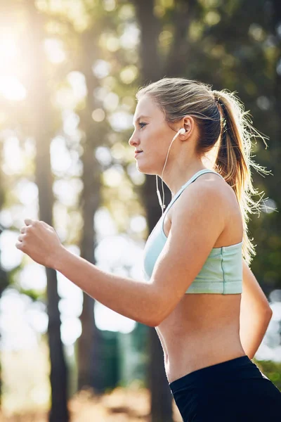 女人带着耳机 在森林里跑步 带着音乐 听着动机在公园里奔跑 户外运动 播客或电台播放的女跑步者 用于运动和健康 体育和能源 — 图库照片