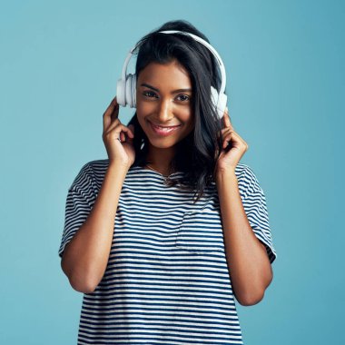 Kadın, portre ve kulaklık stüdyoda müzik, mutluluk ve internet sesi. Mavi arka plan, Hintli kadın ve genç model bir şarkıyı dinleyip, dinleyip, dinleyip, internetten yayınlıyorlar..
