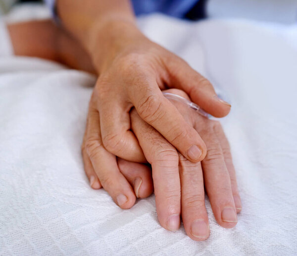 In both good times and bad. Closeup shot of hands clasped in unity and comfort on a hospital bed