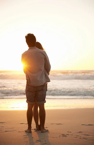 日没時の真の愛 ビーチで一緒に立っている間に夕日を楽しむ若いカップルの後ろの景色 — ストック写真
