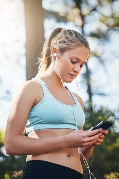 女人带着耳机 智能手机和健康的室外音乐 听着动机在公园里奔跑 拥有歌曲选择 播客或有锻炼 专注和健康的广播流的女跑步者 — 图库照片