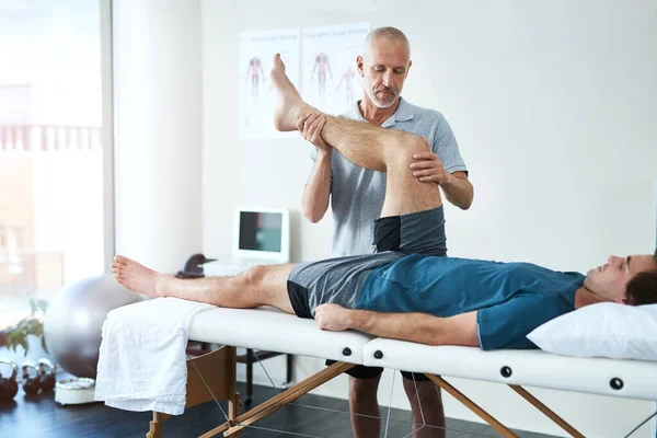 男性和脊医与愈合 腿和康复与医疗问题 康复和保健 有疼痛 伸展腿或理疗的男性 理疗师或顾客 — 图库照片