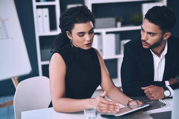 stock image Im not sure how to go about this. two young businesspeople sitting together and having a discussion while using a tablet in the office