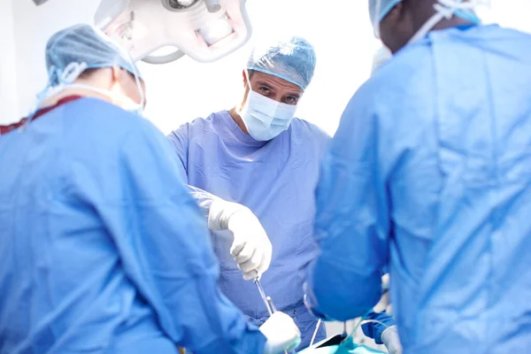 躲在刀下男外科医生在手术室为病人做手术的画像 — 图库照片