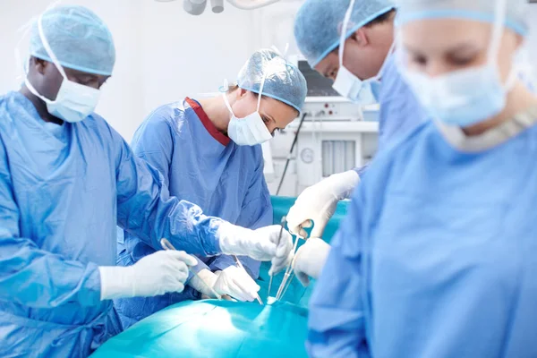 我们在压力下是准确和准确的 手术期间 一组在病人身上工作的外科医生躺在手术台上 — 图库照片
