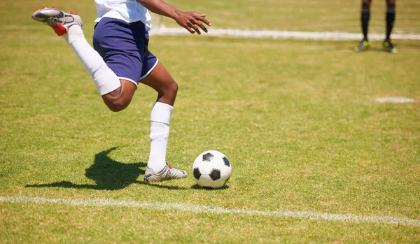 Feet, soccer player and penalty kick on field for goal, competition or game for sports career. Man, football and shooting ball on grass pitch with accuracy for training, workout and contest outdoor.