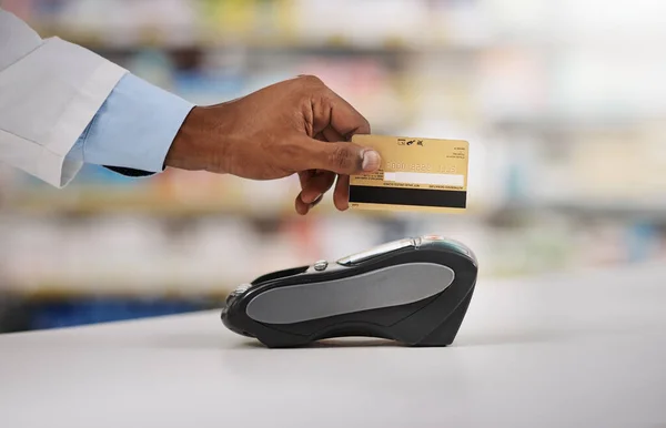 Man, hand and pharmacist with credit card on machine for payment, purchase or swipe in checkout at pharmacy. Hands of person, medical or healthcare expert paying on pos system at pharmaceutical store.