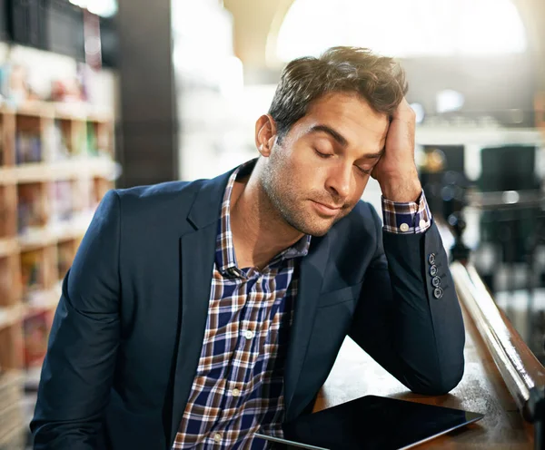Stress, burnout and businessman with a digital tablet in the library while working on a corporate project. Technology, tired and professional male employee with a mobile for a report in the workplace.
