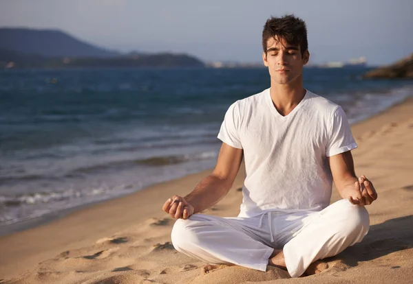他是宇宙中的一员 一个在海滩上做瑜伽的年轻人 — 图库照片