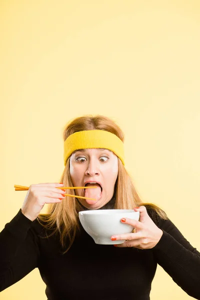 お腹に入りなさい スタジオに一人で立って箸で食べる魅力的な若い女性が — ストック写真