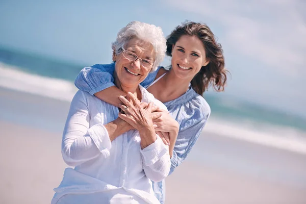 年轻女子和抱着她的大妈或笑 或在海滩上和外面一起 老年公民 幸福的家庭 与成年女儿拥抱 和平或海上旅行自由 — 图库照片