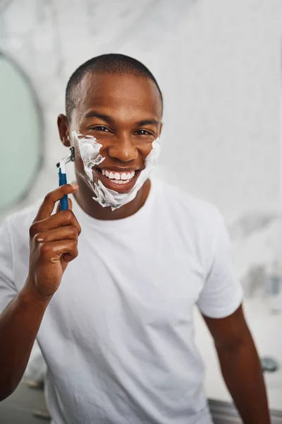 家庭用バスルームでのセルフケアのための鏡の中のブレード 石鹸やグルーミングと黒の男 笑顔とシェービング アフリカの男 泡や顔の毛の除去のためのクリーム カミソリや家で朝の衛生のためにきれいに — ストック写真