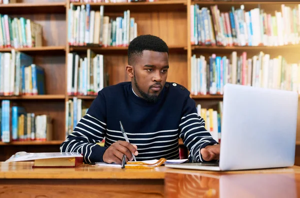 University. library and student on laptop with research, planning or learning for exam, report or focus on studying, goals and education. Black man, college and working on task, essay or scholarship.