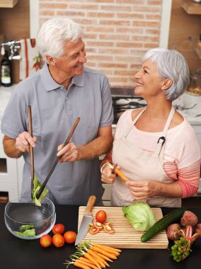 Mutfakta yaşlı bir çiftle yemek, sağlık ve gülümseme salata, aşk ve beslenme için. Yemek, yemek ve yemek için evde sebze doğrayan yaşlı adam ve kadınla mutlu, yardım ve emeklilik..