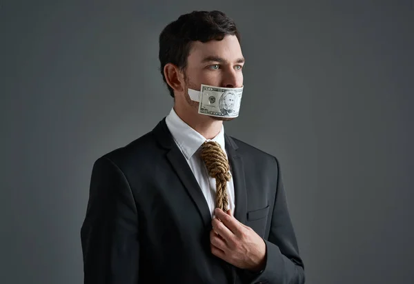 市場における道徳性はどこにあるのか 彼の首とお金の周りにロープを持つビジネスマンのスタジオショット灰色の背景に彼の口の上にテープ — ストック写真
