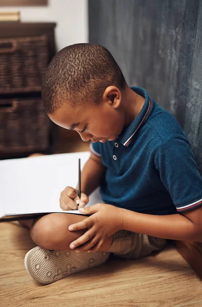執筆は子供に彼らが誰であるか探検する自由を与える 家に座って本を書いている少年が ロイヤリティフリーのストック画像