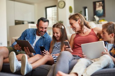 Teknoloji, yayın ve mutlu bir aile internet, sosyal medya ve iletişim için koltukta. Gülümse, kaynaşma ve evde online oyunlar için tablet ve telefonla bir anne, baba ve çocuklar.