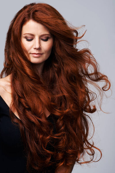 Wind in hair, ginger and face of woman in studio for keratin treatment, wellness and growth on gray background. Beauty, hairdresser mockup and female model with shine, healthy and natural hairstyle.