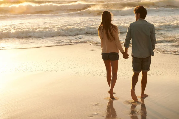 ビーチでの愛 夕暮れ時にビーチを歩く若いカップルの眺め — ストック写真