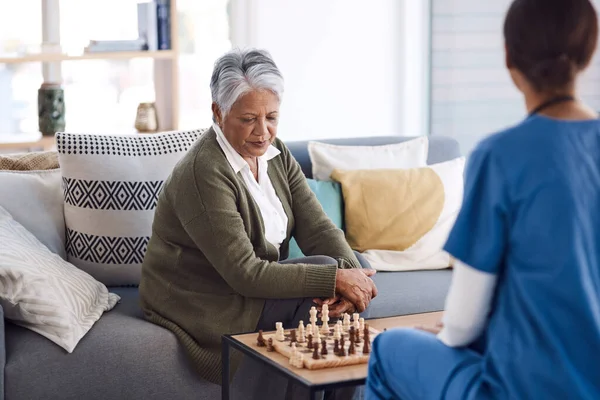 Nurse, chess or old woman in nursing home for healthcare, problem solving skills or mental health recovery. Relaxing, caregiver or focused mature patient thinking of solution or playing board games.