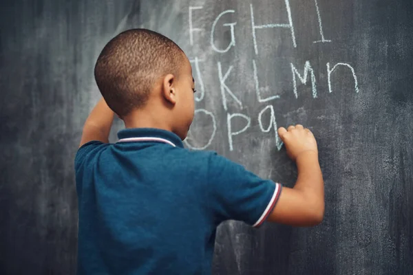 我今天要练习字母 一个在家里黑板上写字的小男孩 — 图库照片
