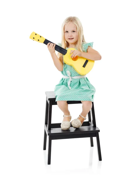 彼女の才能を育成する スタジオショットの可愛いです女の子遊びとともに彼女のおもちゃのギターのために白い背景 — ストック写真