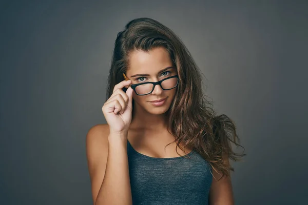 2倍の目をして スタジオショットの魅力的な若いです女性Peering上の彼女の眼鏡に対して灰色の背景 — ストック写真