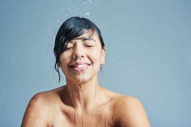 Stüdyoda suyu olan bir kadının duşu, yıkaması ve yüzü mavi arka planda, sağlık, temizlik ve bakım için. Cilt bakımı, güzellik modeli ve hijyen, hidrasyon ve kişisel bakım için mutlu bir kadın..