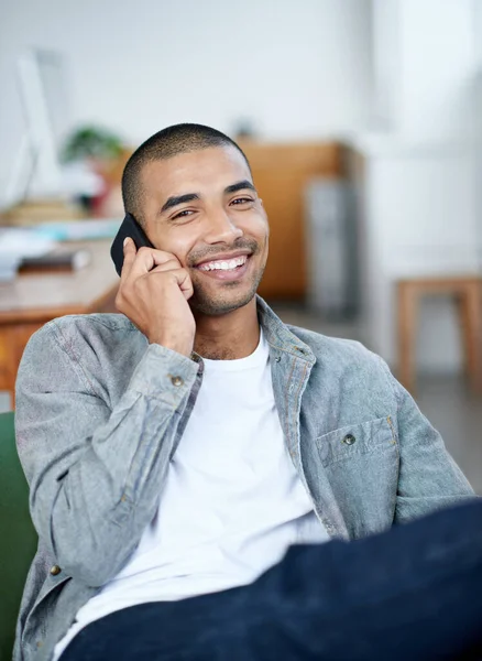 Getting good news. a handsome young office worker talking on a cellphone while sitting in an office