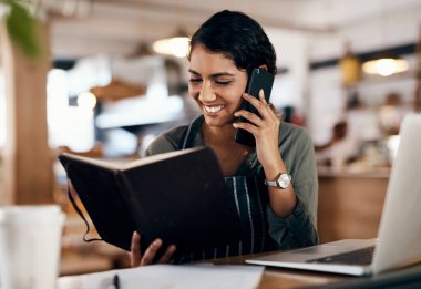 Kafe menüsünü taze ve güncel tutuyorum. Kafede çalışırken akıllı telefon kullanan genç bir kadın.