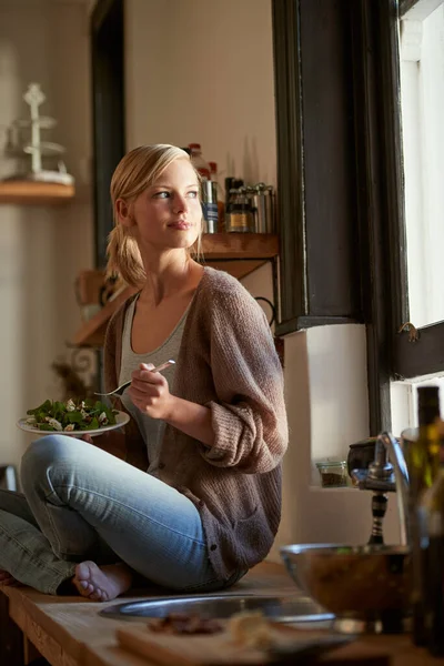 stock image She always starts her day with the freshest ingredients. Full length shot of a young woman eating a bowl full of leafy greens in a rustic kitchen