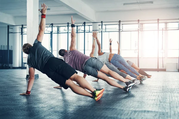 stock image Fitness, group class and athletes doing a exercise in the gym for health, wellness and flexibility. Sports, training and people doing side plank exercise challenge together in sport studio or center