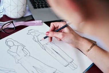 Kadın, el ve moda tasarımcısı ofis masasında plan, fikir ya da çizim yapmak için kağıt üzerine çizim yapıyor. Yeni başlayanlar için yaratıcı kadın, sanatçı ya da grafik tasarımı sunan bir el..