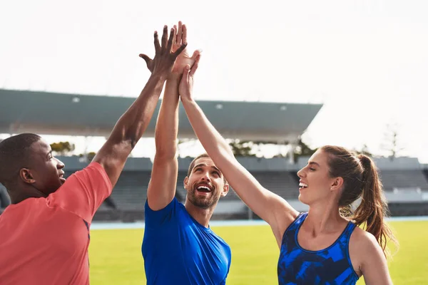 Diversity, team and high five on stadium track for running, exercise or training together in athletics. Group touching hands in celebration or solidarity for exercising, run or winning in fitness.