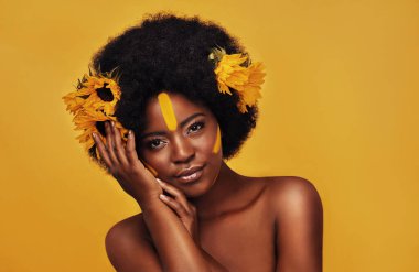 Stüdyoda güzellik, yaratıcı ya da bahar için siyah kadın portresi olan doğal, ayçiçeği ve saç. Makyaj, kozmetik ve çiçekli sarı arka planda sanat, kendini sevme ya da ışıltı için bir model..