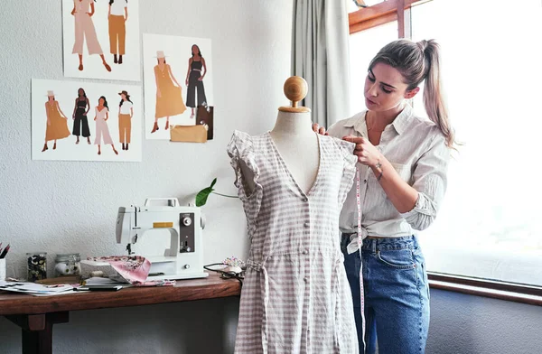 Fashion, design and woman with mannequin, measuring tape and sewing machine at creative small business. Focus, creativity and tailor with dress on doll for clothes, designer in textile startup studio.