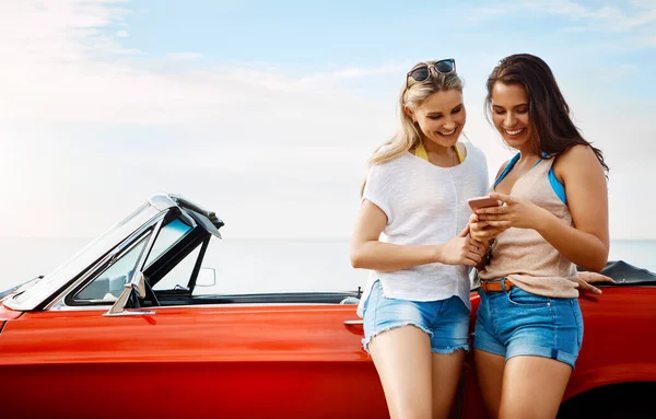 stock image Travel more, worry less. two friends using a smartphone on a summers road trip