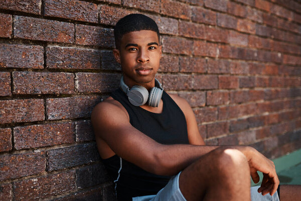 I have the determination to go for all my goals. Portrait of a sporty young man sitting against a wall outdoors