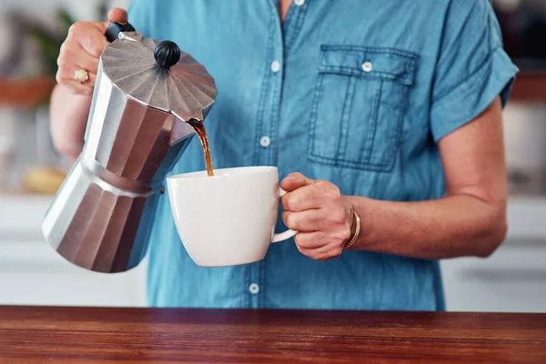 stock image Starting her morning with a little bit of caffeine. an unrecognizable senior woman pouring herself a cup of coffee while standing in the kitchen