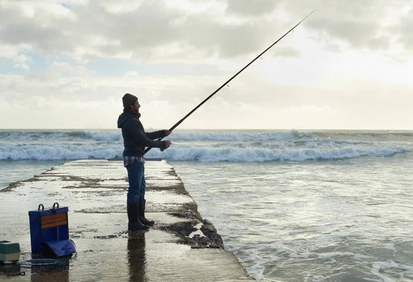 大きなキャッチのために彼の時間を取る 海の桟橋から一人の漁師が釣りをしていて — ストック写真