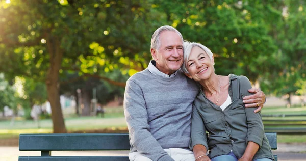 stock image Senior couple, bench and happy outdoor in a park with love, care and support in marriage. A elderly man and woman hug in nature with a smile for quality time, healthy retirement and freedom to relax.
