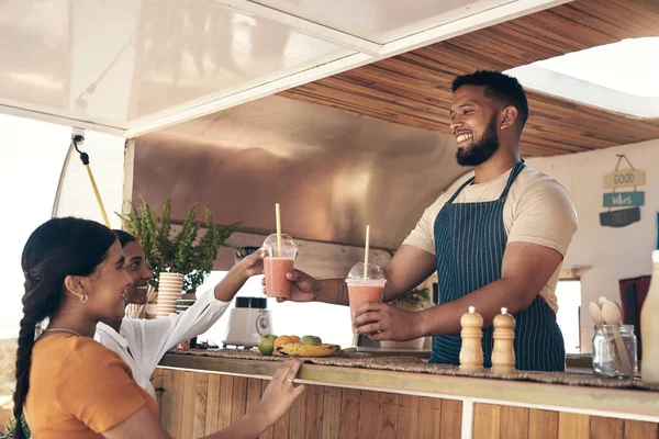 stock image I hope you enjoy it ladies. two friends talking to the owner of a food truck while buying smoothies