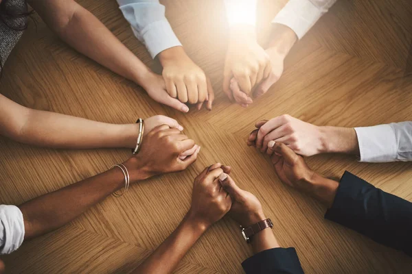 stock image Support, diversity and people holding hands by a table at a group counseling or therapy session. Gratitude, trust and friends in a circle for praying together for religion, community and connection