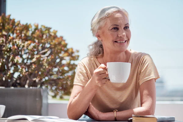 Everyday should start out this way. a mature woman having coffee on the balcony at home