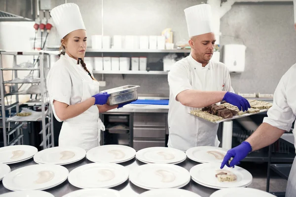 Careful plating for service. chefs preparing a meal service in a professional kitchen
