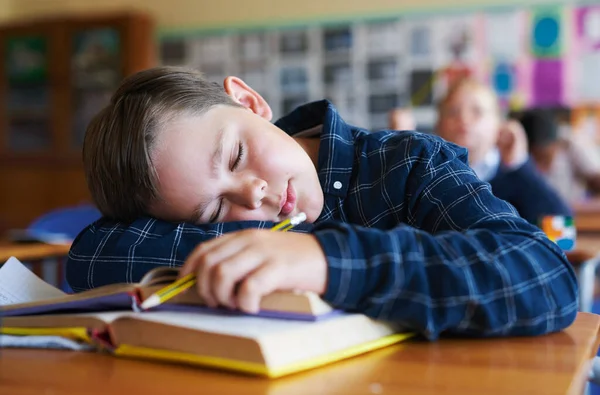 昨晚我睡得不好 一个小男孩在学校的教室里的课本上睡着了 — 图库照片