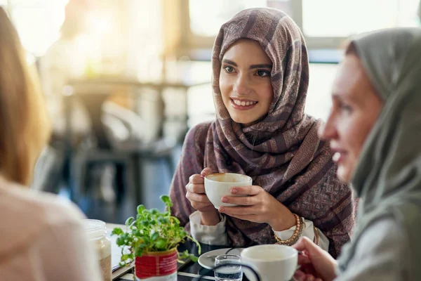 朋友们 微笑着和穆斯林妇女在咖啡店里 牵线搭桥 聊着天 咖啡馆 快乐的伊斯兰女孩 团体或人们在餐馆里聊天 谈话和讨论社交聚会 — 图库照片