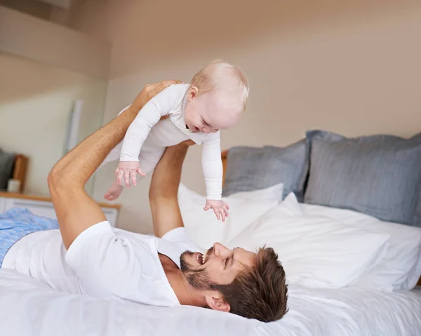 stock image Safe in daddys hands. a father lying on a bed holding his baby girl up in the air