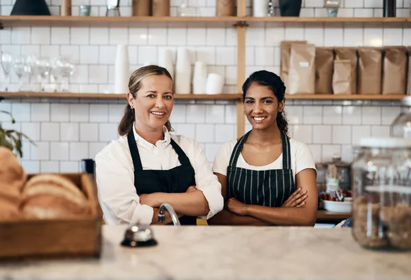 It takes a great team to run a great bakery. Portrait of two confident women working behind the counter of a cafe