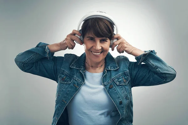 保持冷静 听你最喜欢的歌 一个头戴灰色背景耳机的老年妇女的工作室肖像 — 图库照片